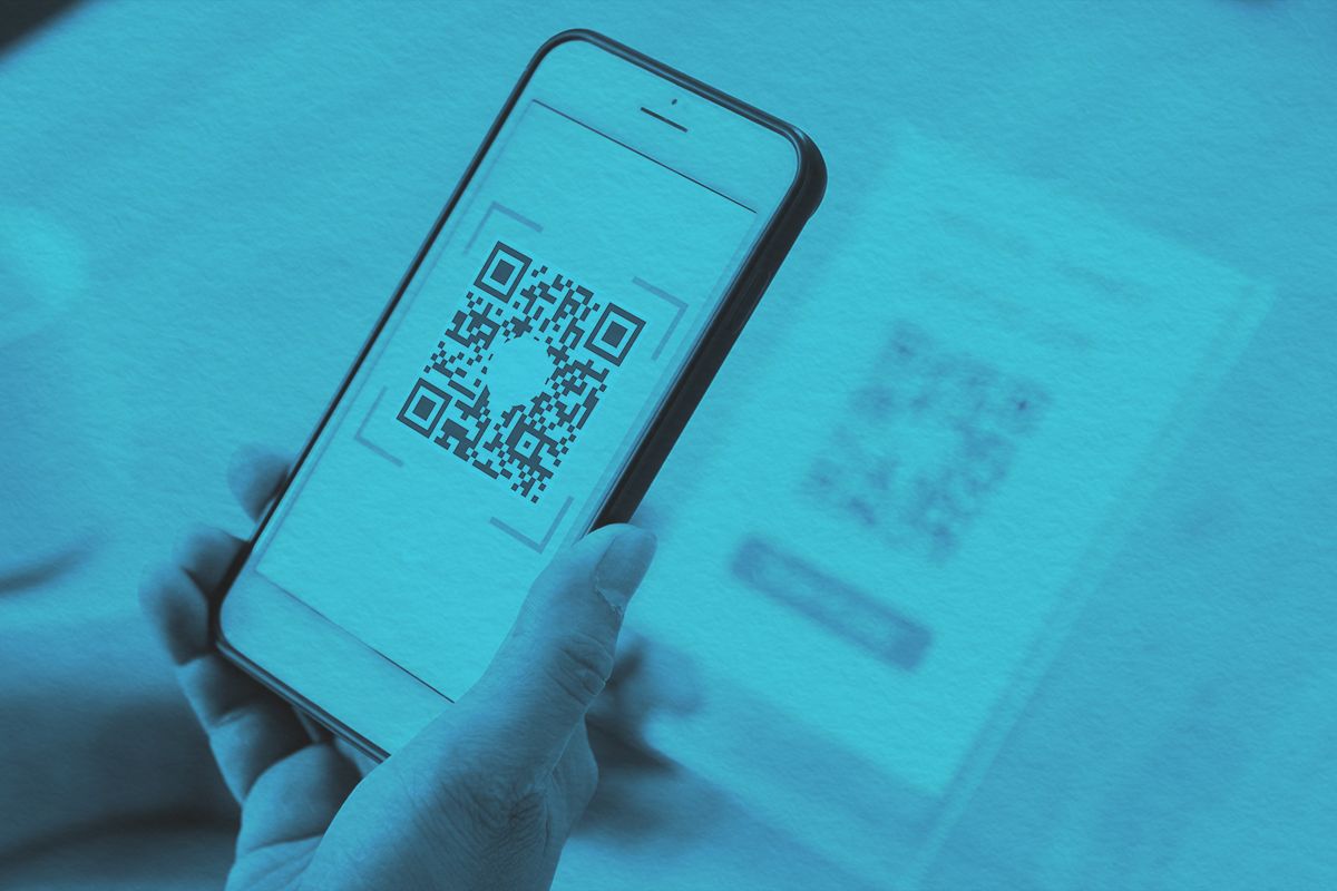 man's hand scanning QR code through mobile phone