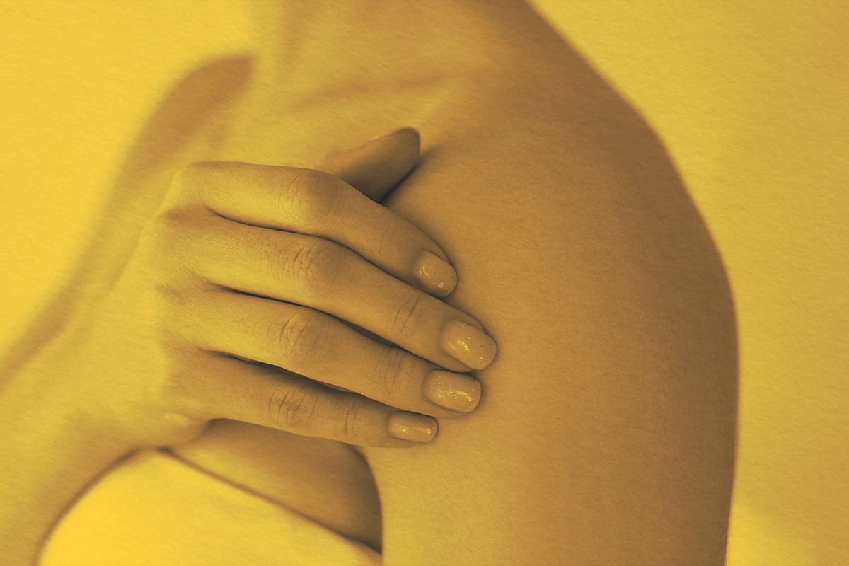 Close-up of a woman rubbing her bare shoulder