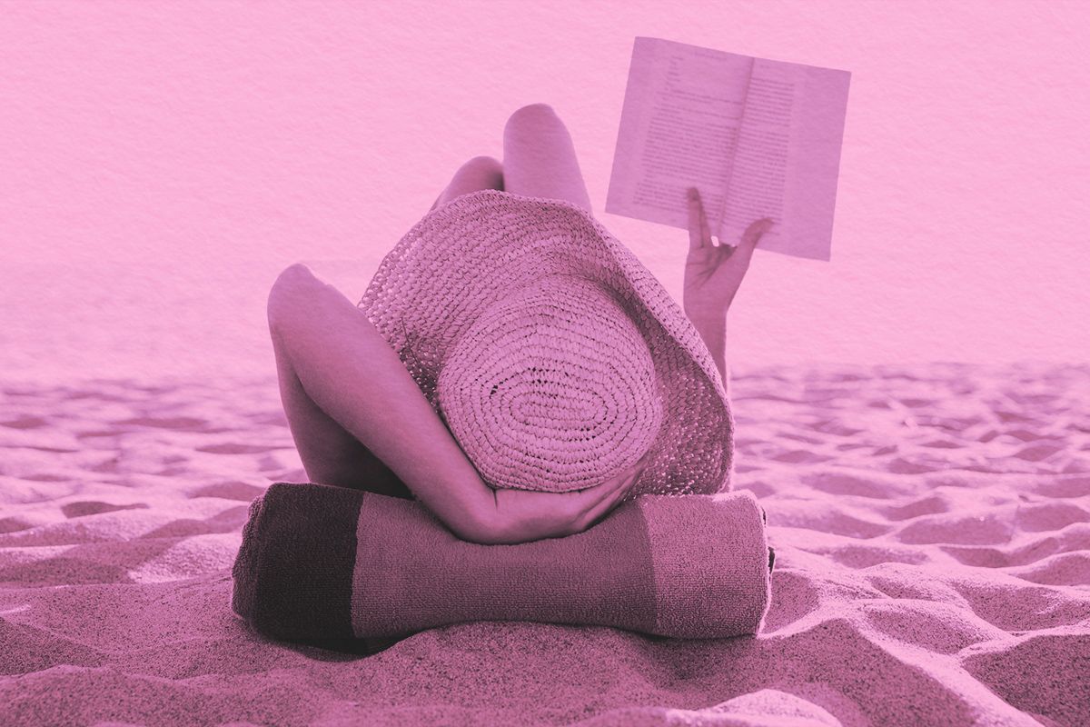 Woman lies on the beach reading a book
