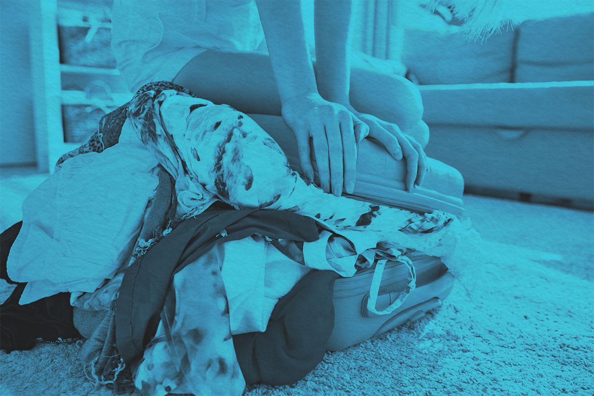 Girl packing overflowing suitcase for travel