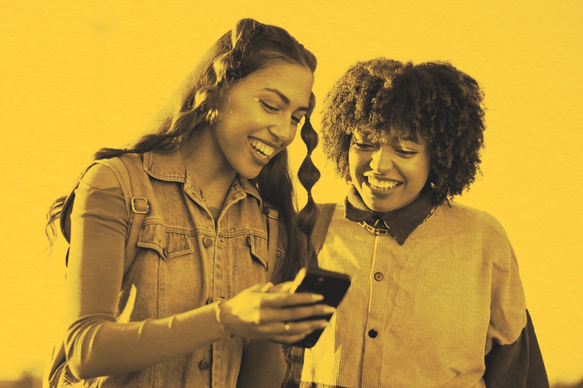 Two young adults laughing while looking at a phone