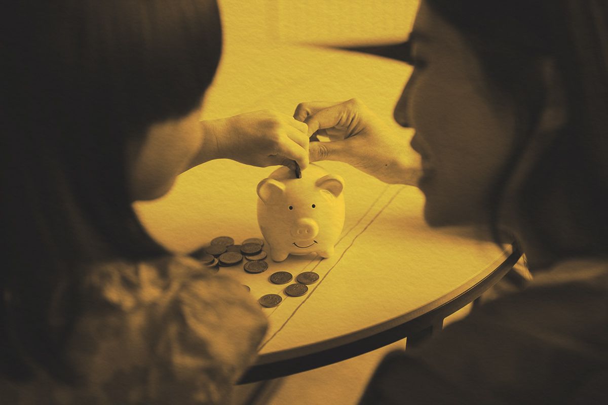 Mother and daughter putting money in a piggy bank