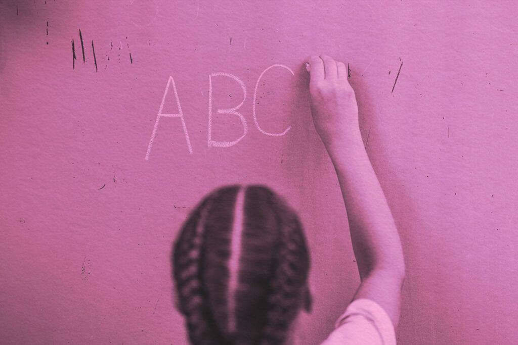 Student writes alphabet letters on school board