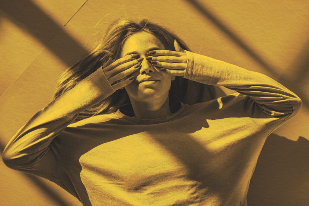 woman lying on the floor and covering her eyes