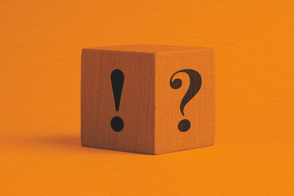 A wooden cube with an exclamation mark and a question mark on the side