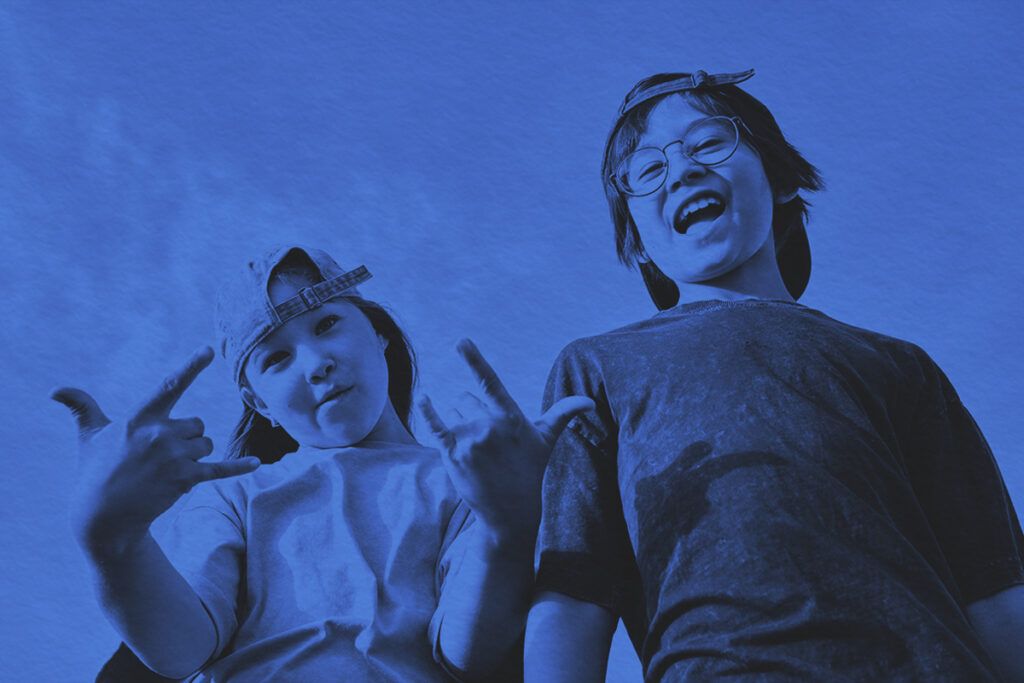 A boy and a girl make faces at the camera against the background of the sky