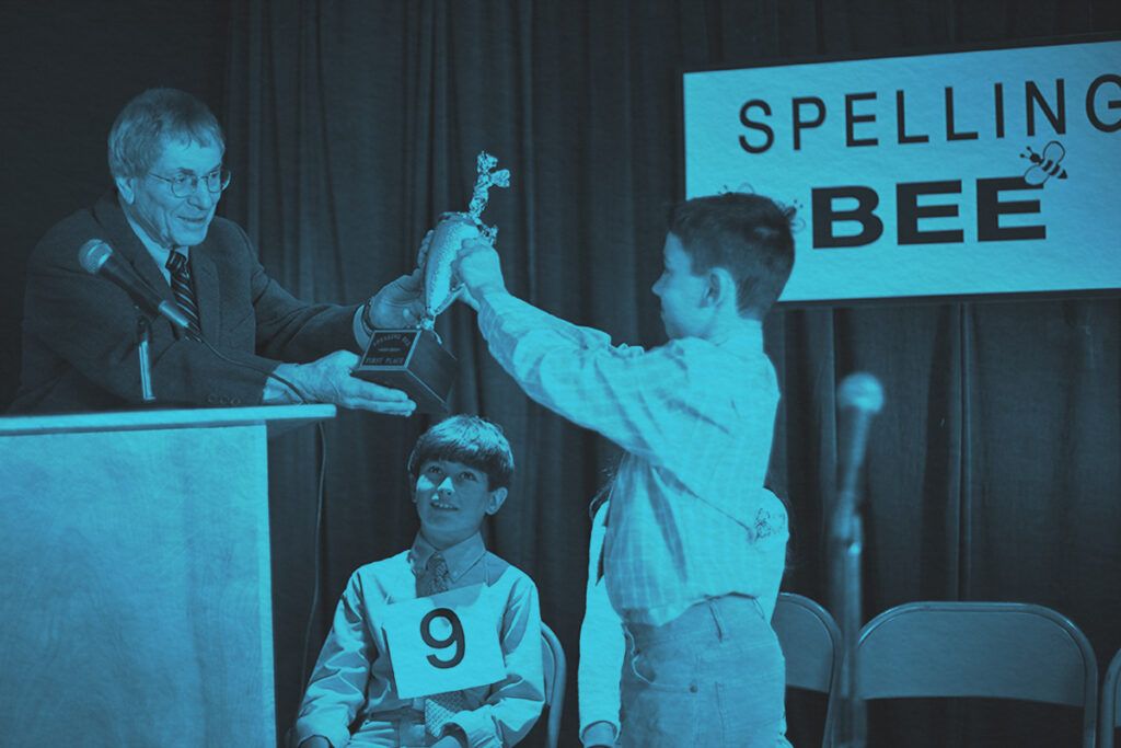 Senior man handing spelling bee trophy to a young boy