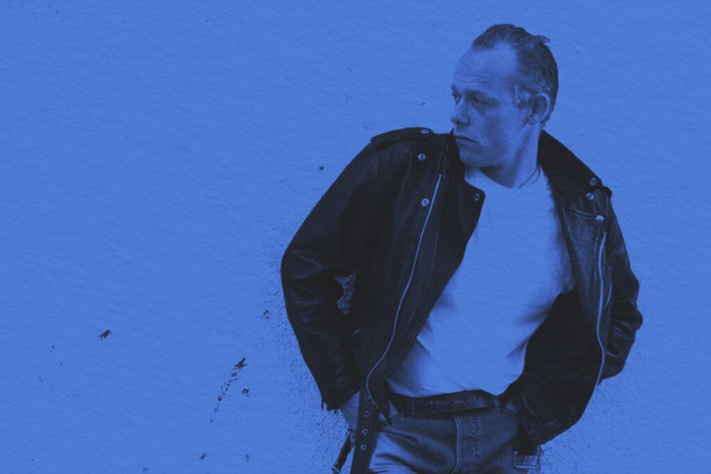 Man posing against a wall in 1950's greaser wear