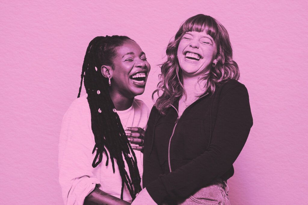 Two women laughing cheerfully while standing together