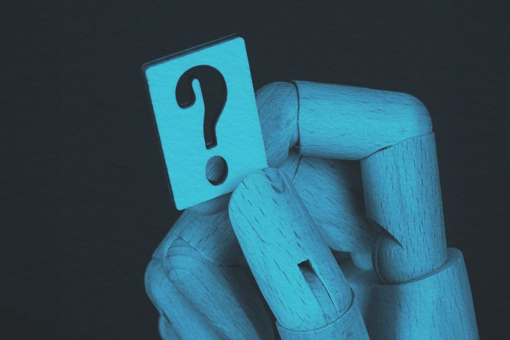wooden hand holding a question mark
