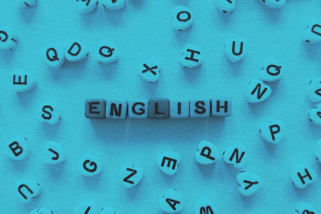 Square alphabet blocks neatly aligned in the center to spell out the word "ENGLISH" with scattered heart blocks with various letters surrounding