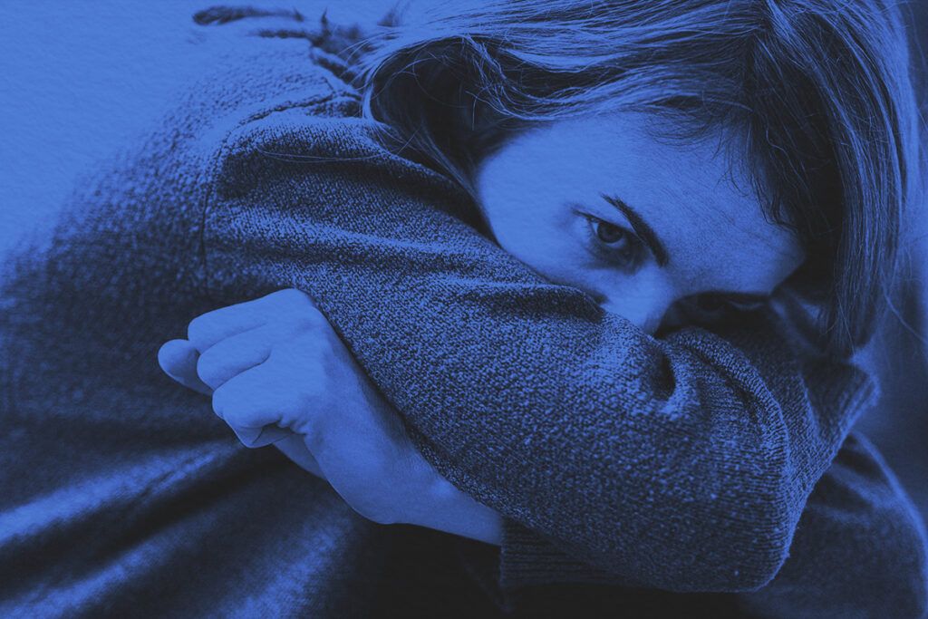 Close-up of nervous woman curled up with her arms wrapped around her