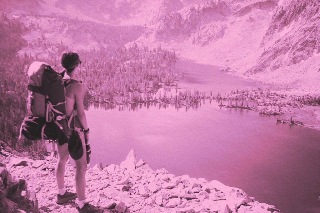 A woman with a backpack looking at a lake